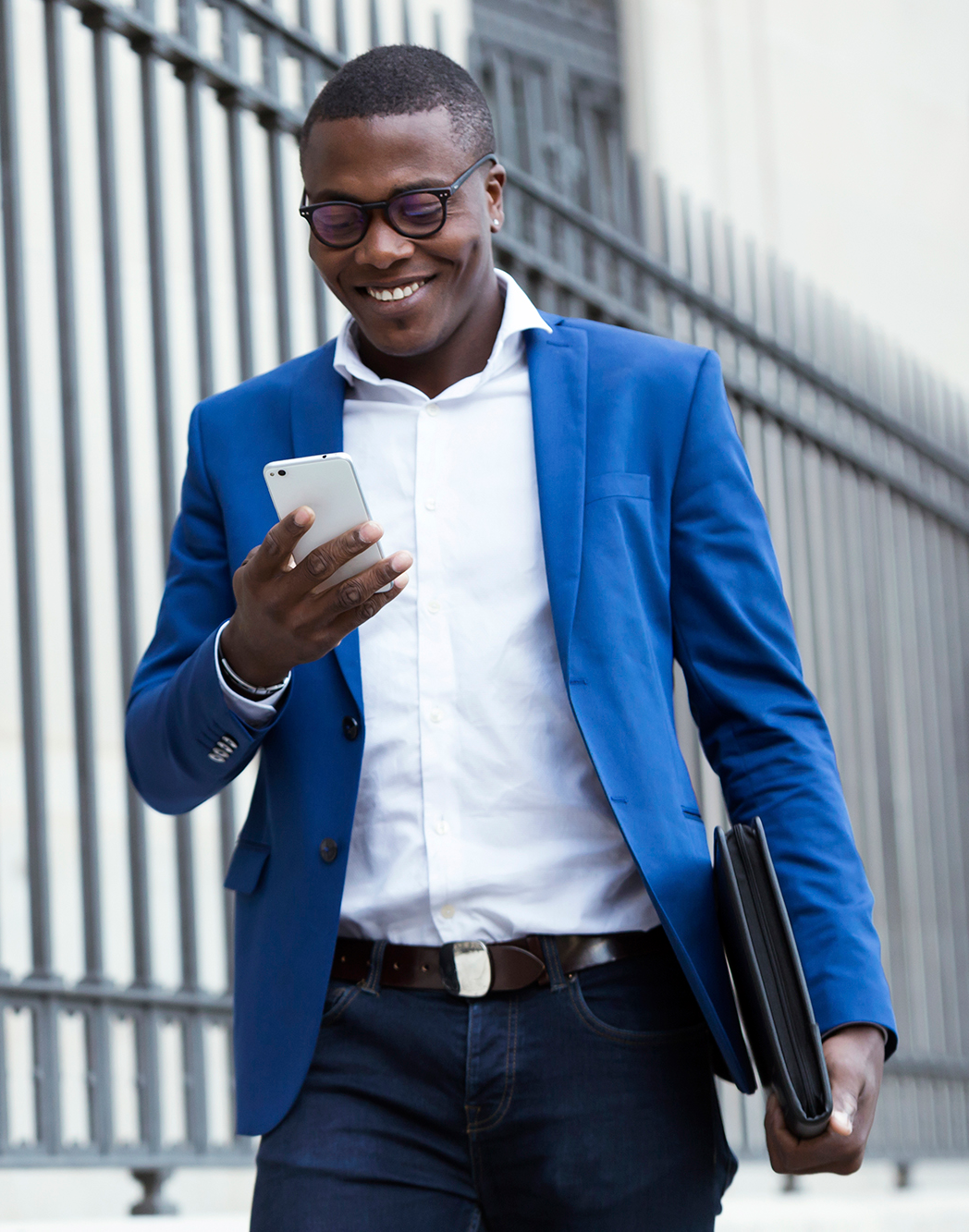 A man in a suit walking down the street with a notebook and briefcase A man in a suit walking down the street with a notebook and briefcase