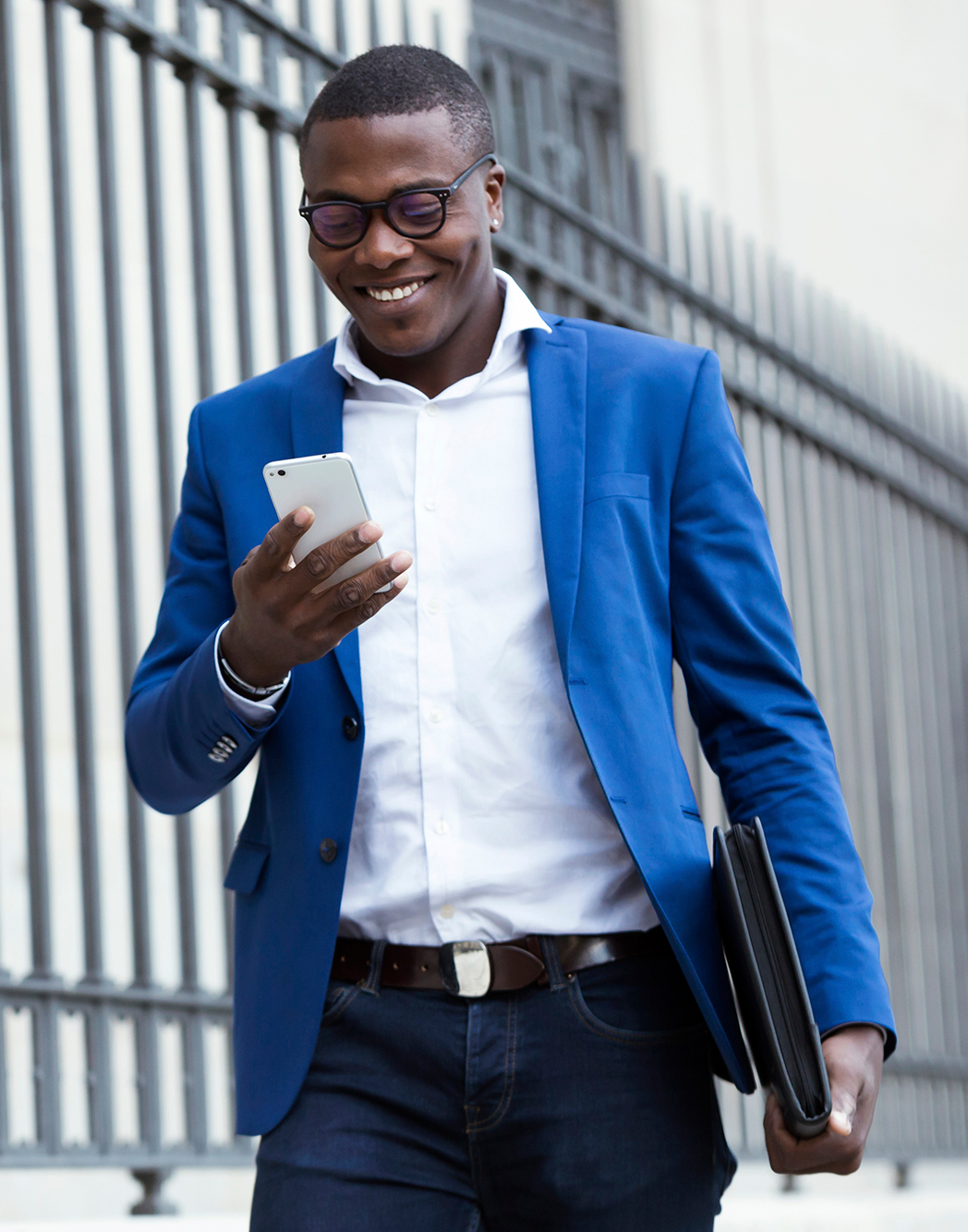 A man in a suit walking down the street with a notebook and briefcase